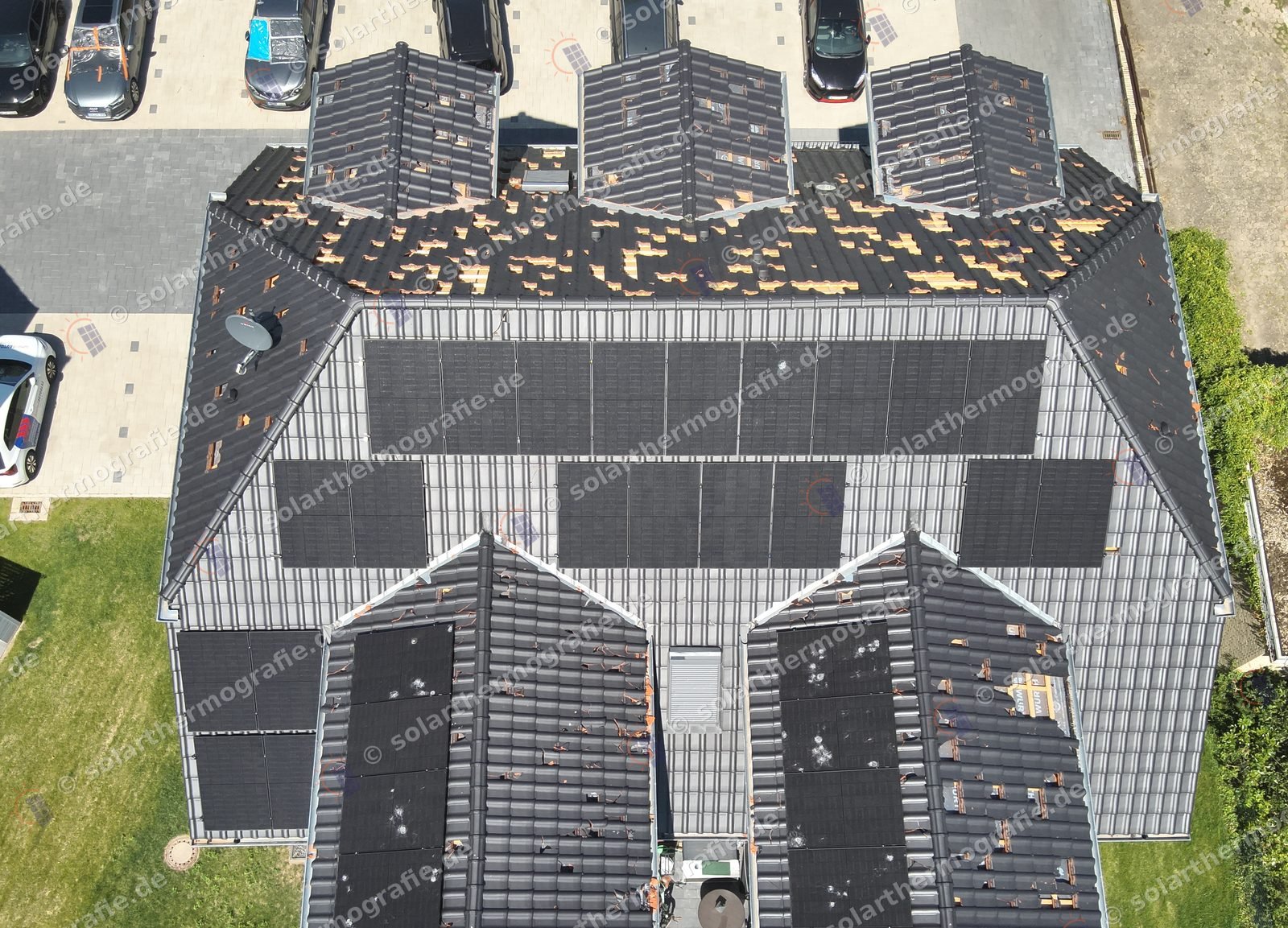 Mehrfamilienhaus mit Hagelschaden an Dacheindeckung und Photovoltaikanlage aus der Luft