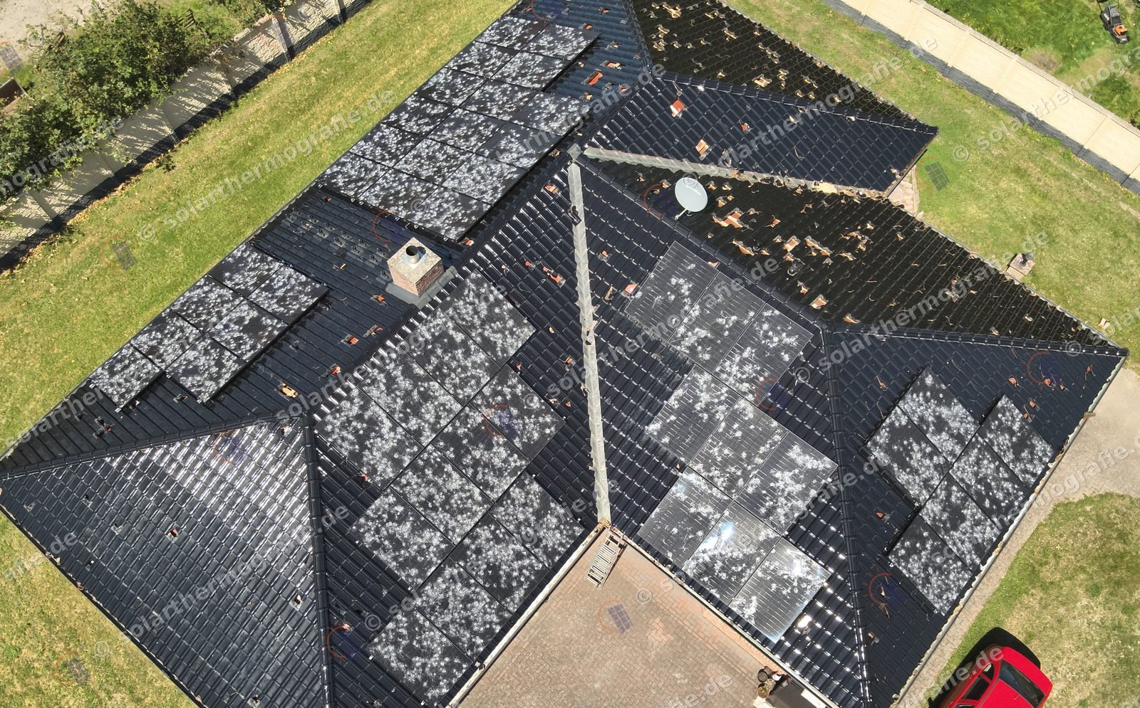 Wohnhaus nach Hagelschlag mit zerschlagenen Dachziegeln und flächig beschädigten Solarmodulen